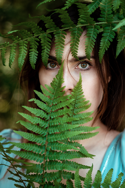 kolorowe zdjęcie twarzy kobiety przysłoniętej liściem paproci - artystka Ada Kućmierz